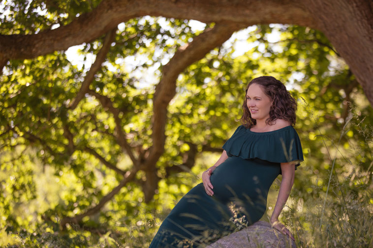 gravid kvinde i blå kjole i skov