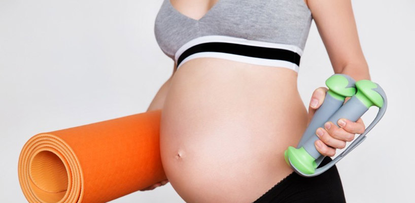 gravid kvinde med vægte og træningsmåtte