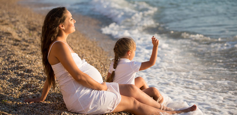 gravid kvinde med barn ved strand