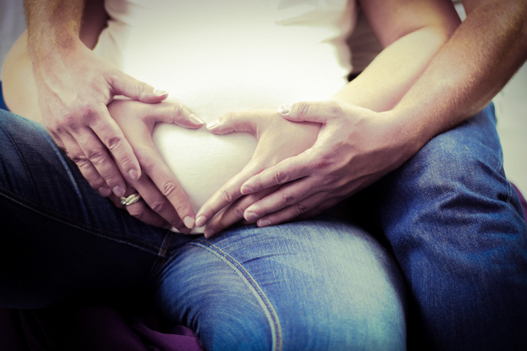 mand og kvindes hænder former hjerte på gravid mave