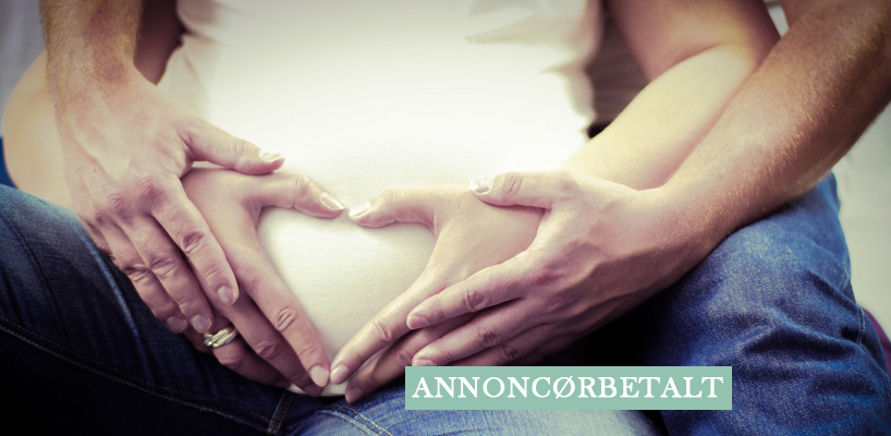 Mand og kvinde former hjerte med hænderne på gravid mave