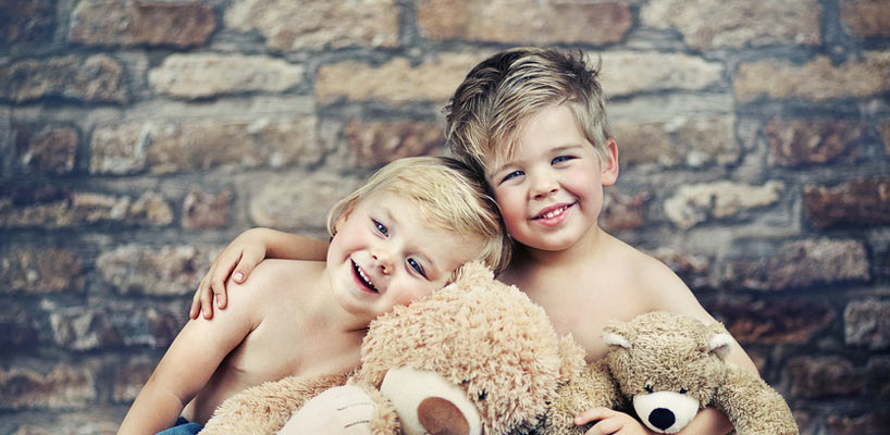 to drenge sidder med bamser op ad mur