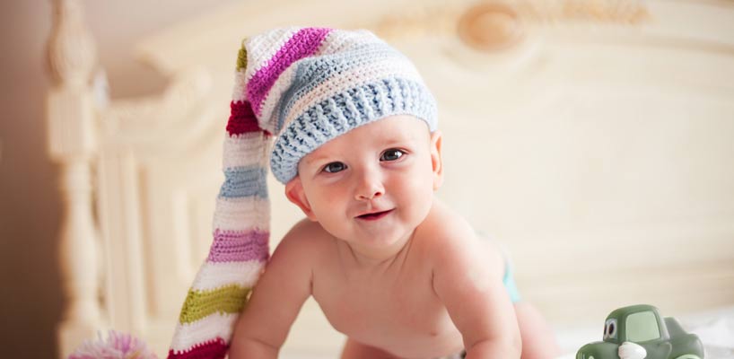 baby med stor strikket strømpe på hovedet